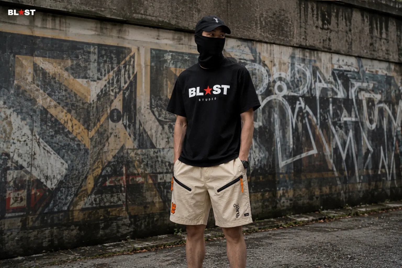 Model in the ink tee and bone tech shorts in front of a painted yard wall