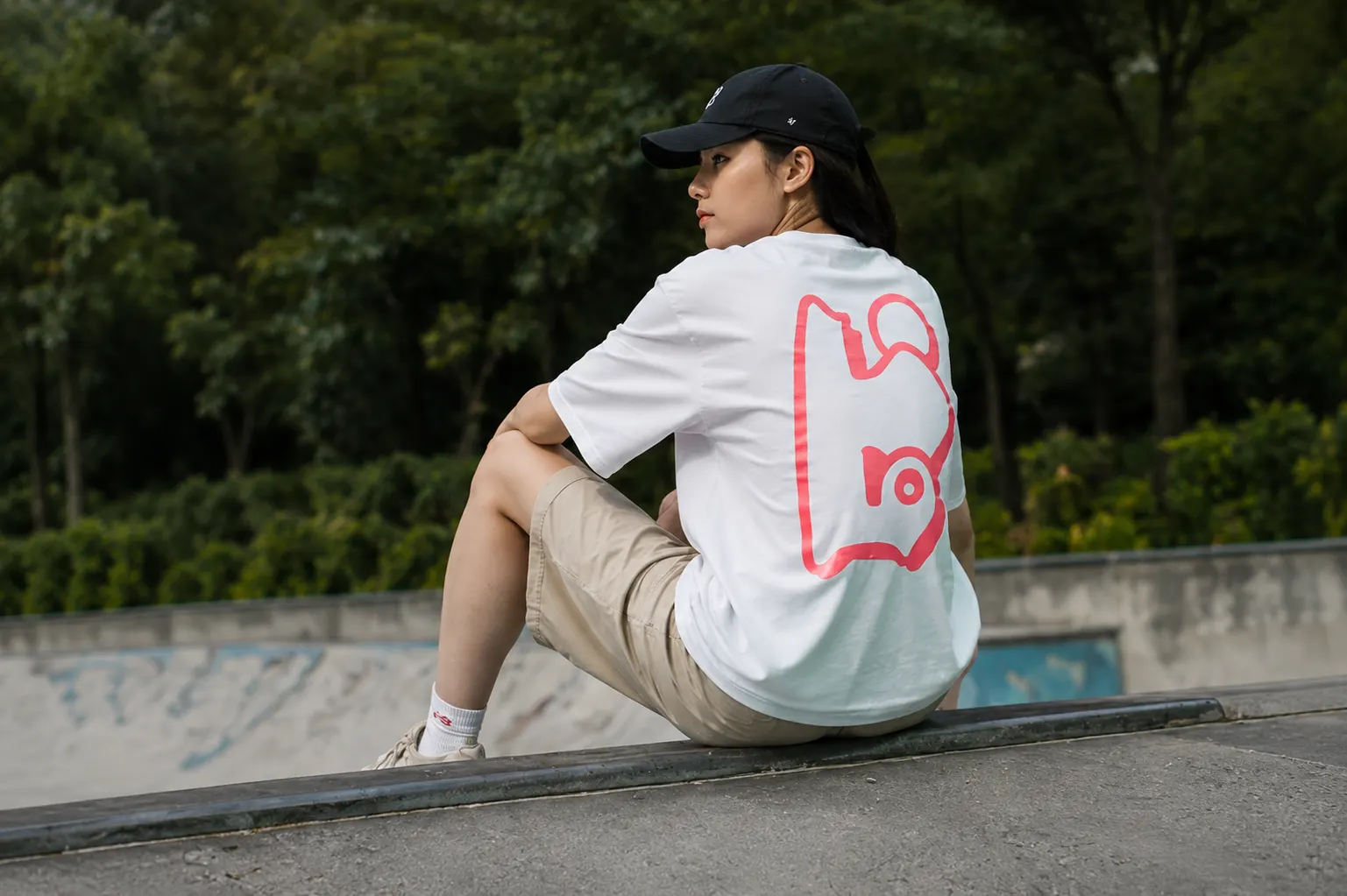 Seated model showing the bone tee back print in pink